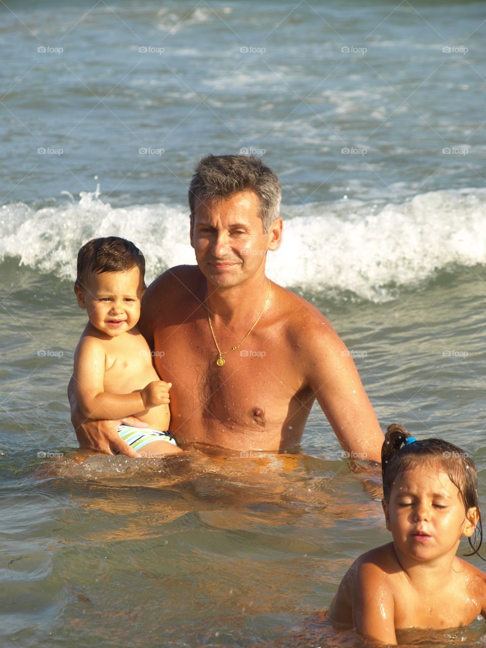 Shirtless man with children in the sea