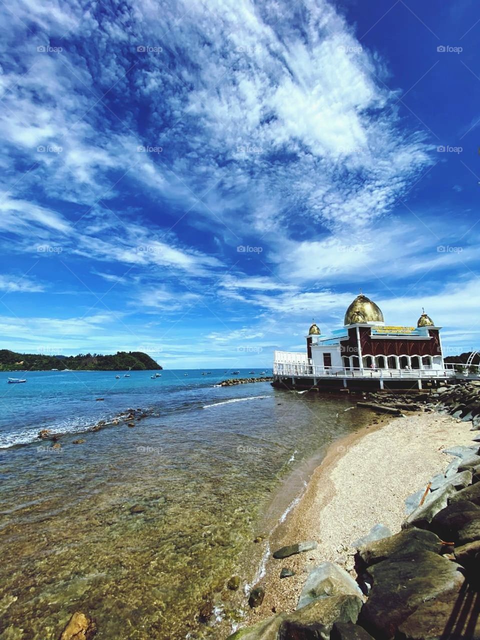 the exterior of the mosque building by the sea with a blue sky and sunny weather