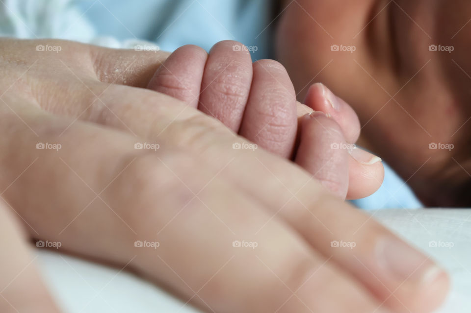 Newborn boy holding his mother's finger 