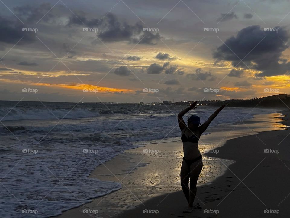 Woman happy with the beautiful sunset on the beach