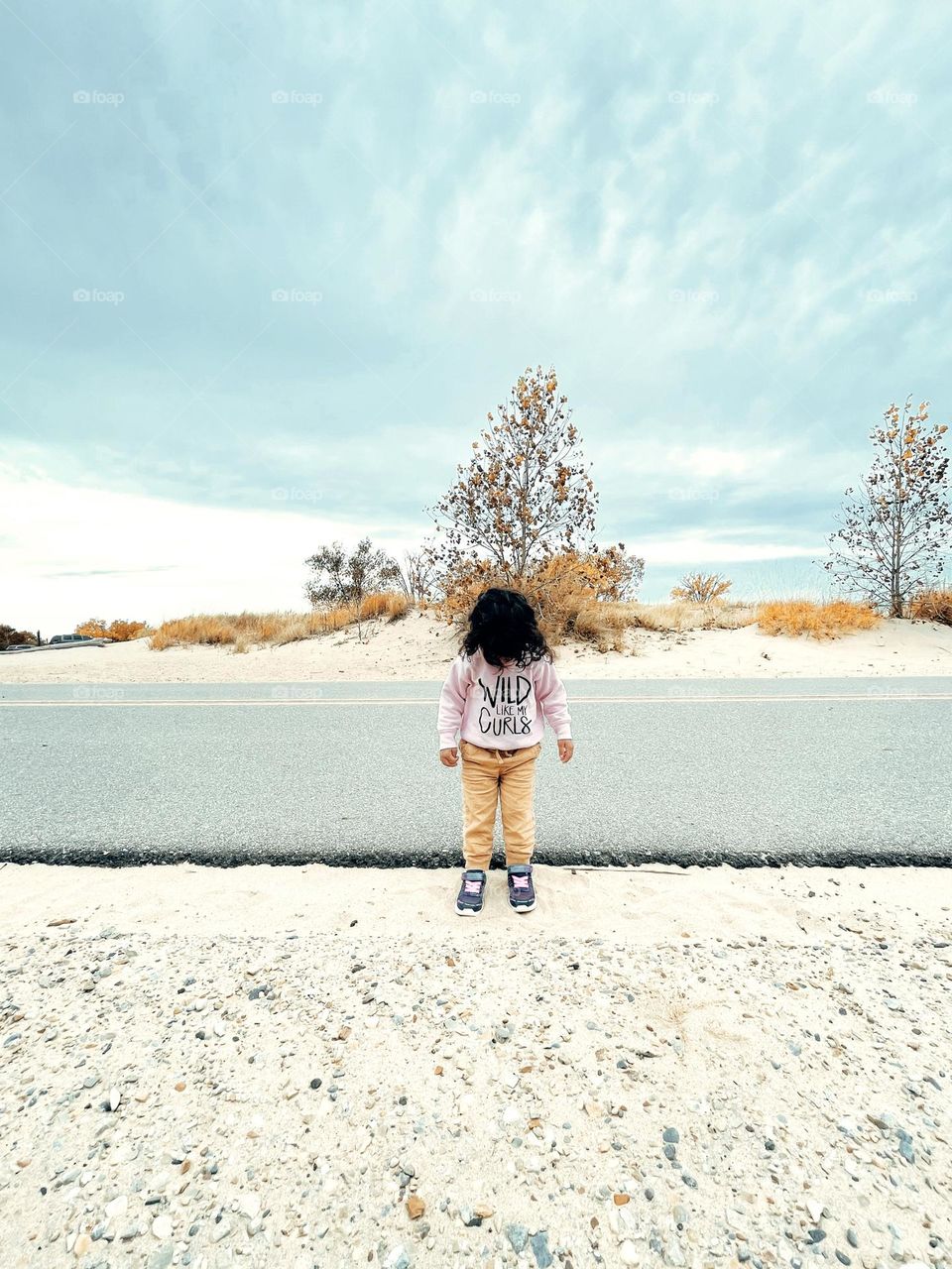 Wild like my curls, little girl with curly hair standing by the road, hair as an accessory, wild curly hair on toddler girl, toddler with crazy hair, toddler looking down on beach road