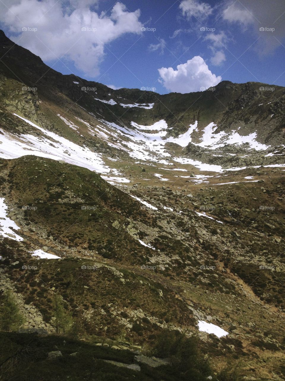 vallata parzialmente innevata della cima della montagna riaffiorano erba e rocce.
Partially snow covered valley in the top of the mountain resurface grass and rocks.