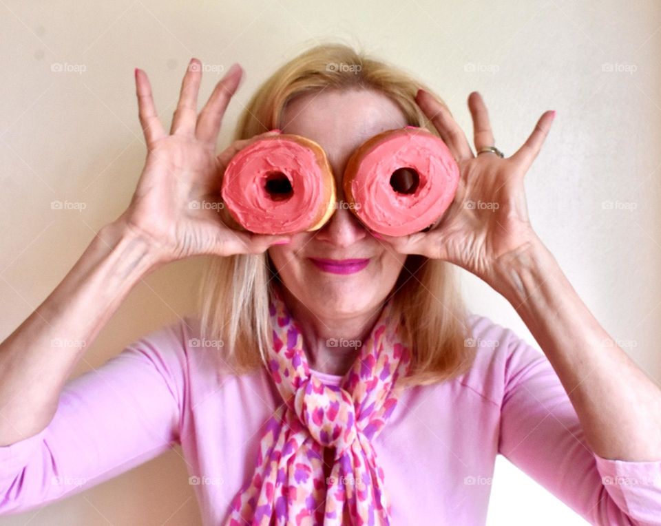 Woman holding donuts in front of her eyes 