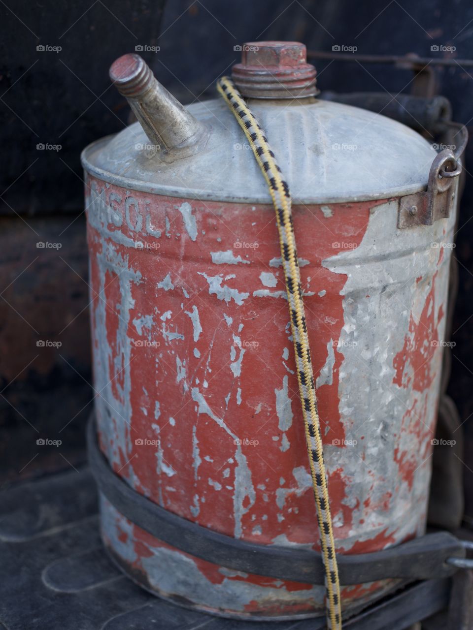An old circular spare gas can strapped to an old truck 