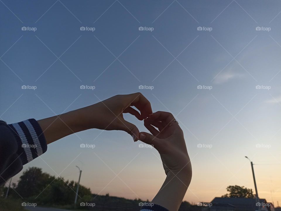 Heart made out of hands on sky background