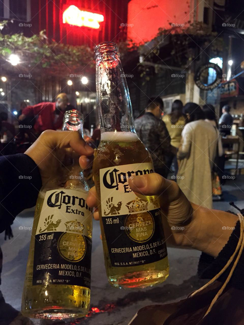 2 corona beers in a background of a nice bar, filled with lights and people