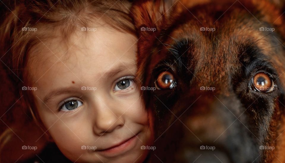 Little girl and German shepherd close up portrait with accent on the eyes 