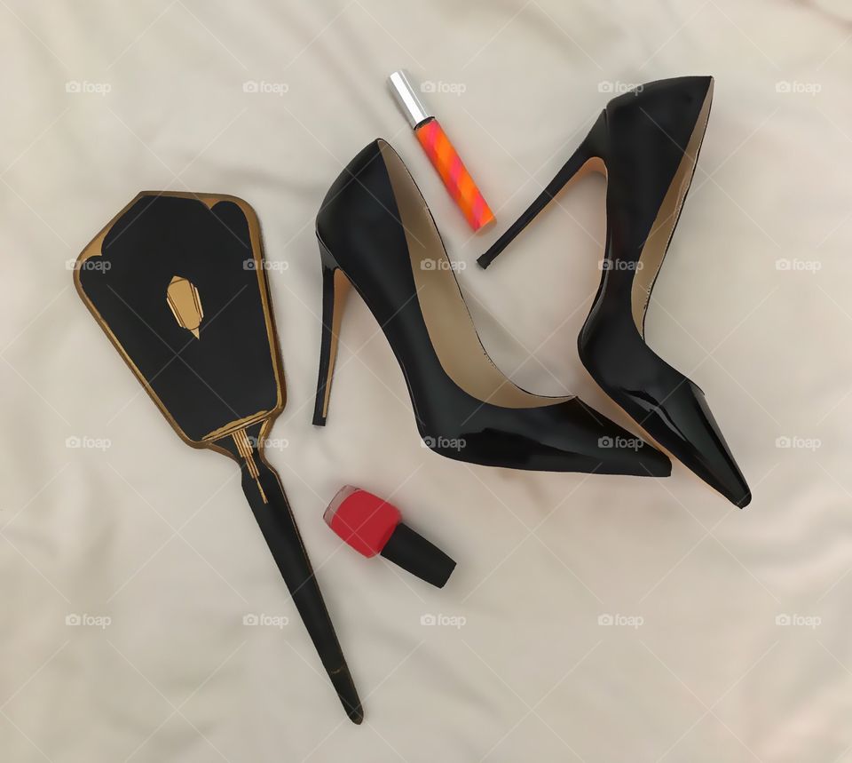 Black leather stilettos and cosmetics in a fashion lay out.
