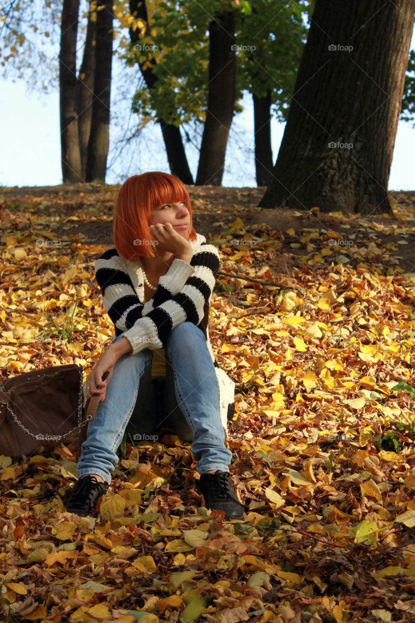 Young woman sitting on autumn leaves