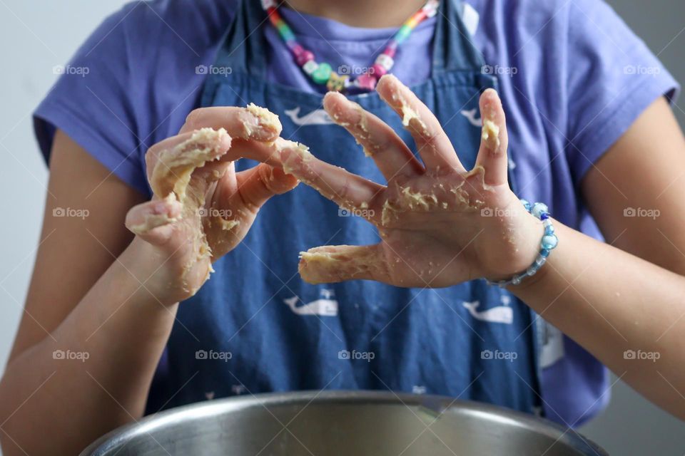 Child is cleaning her hands from a sticky dough