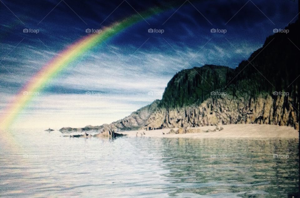 Paisagem linda do arco-íris as pedras e a água 