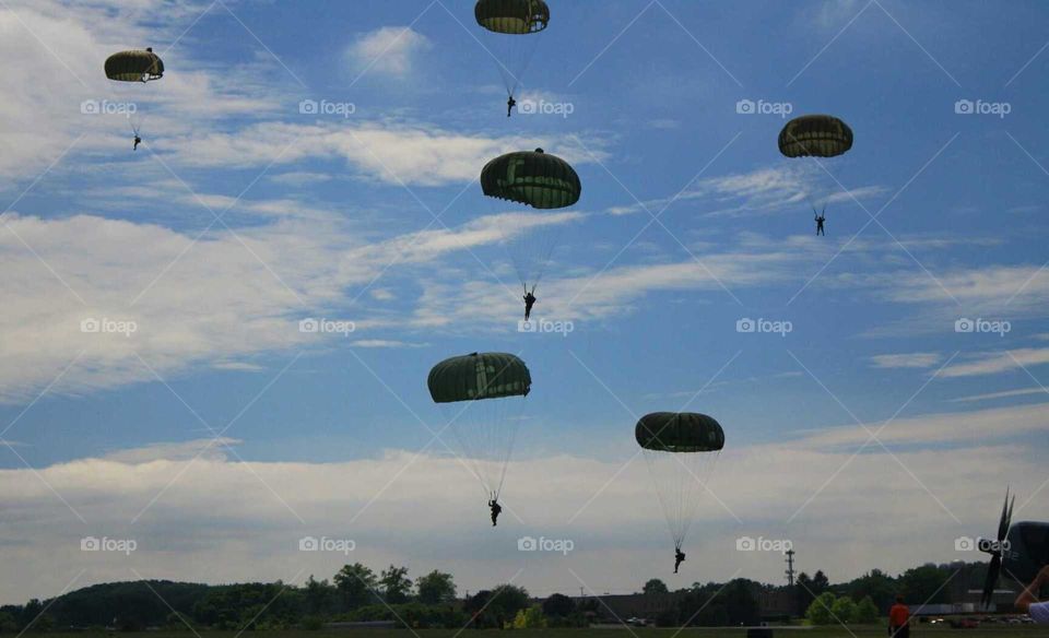 WWII reanactors parachute skydivers in blue sky