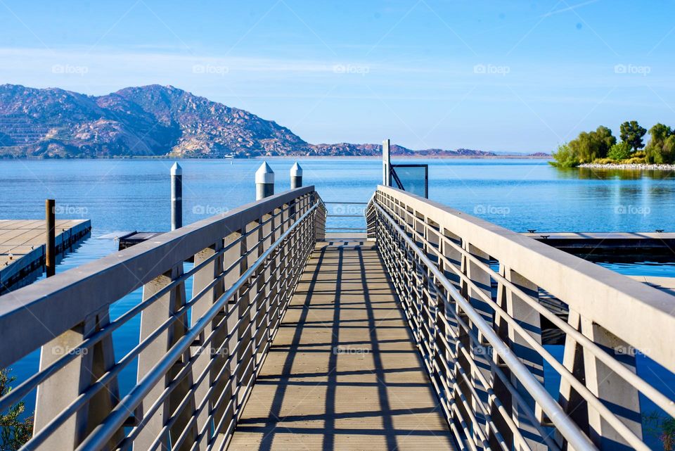 A  wooden dock that leads to a beautiful lake with a view 