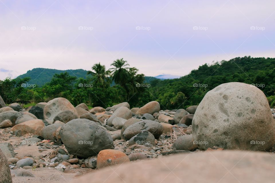 The stones spread out on the banks of the swift river, the stones appeared after the floodwaters hit the river so that the layers of soil were eroded and only rocks were visible.