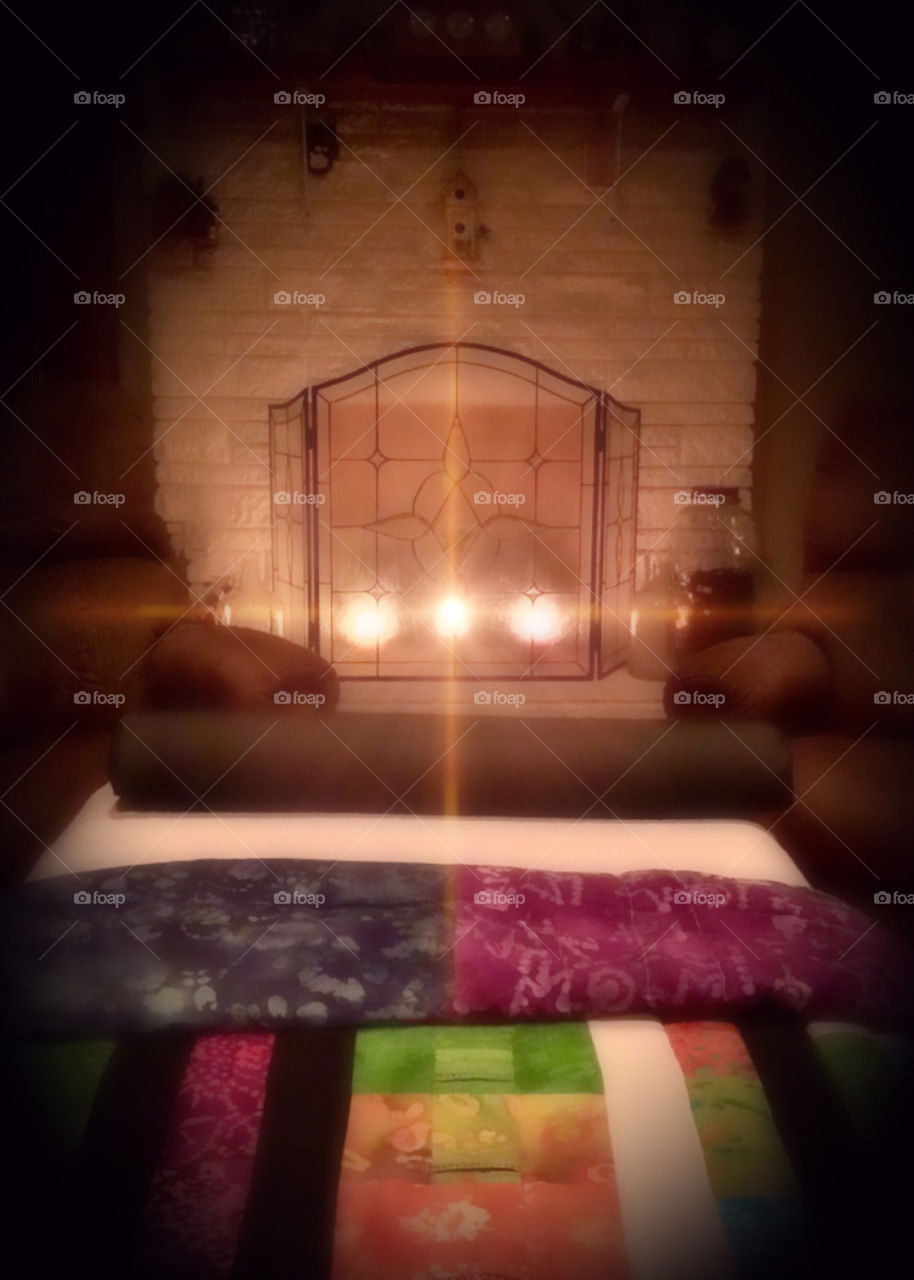 Fire light candles in meditation reiki treatment room with rainbow log cabin quilt gives feel of country home comfort and relaxation spiritual tranquility.