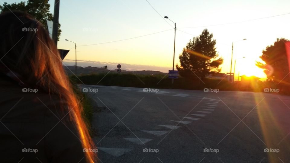 a woman walking along the street at sunset