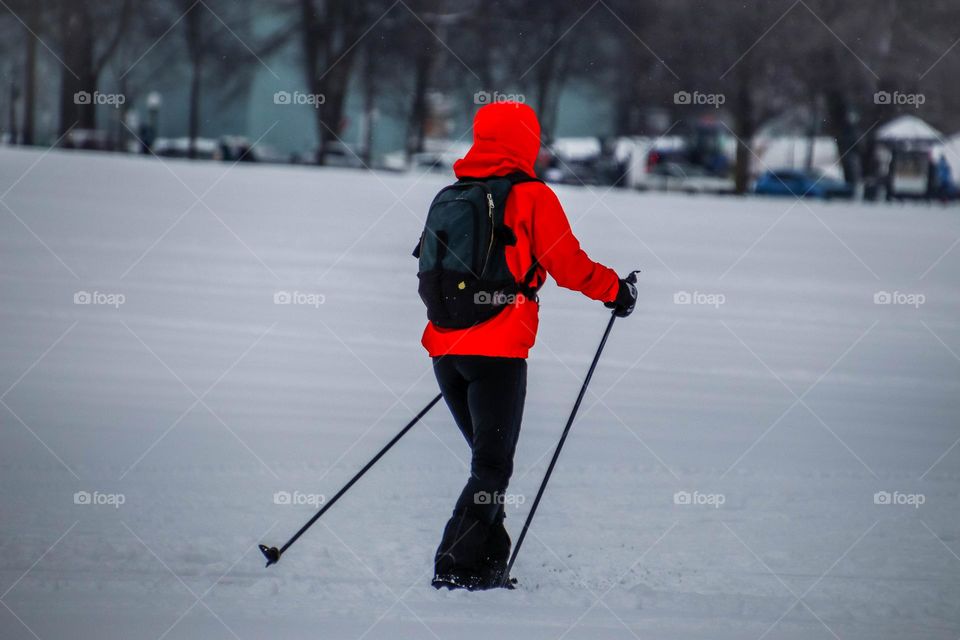 Person in bright red jacket is skiing in the park