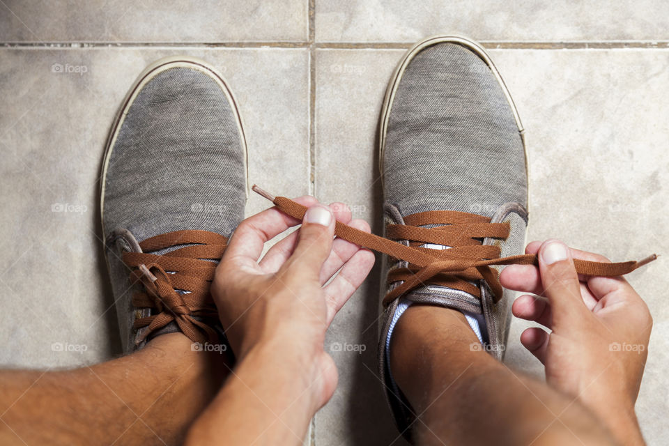 Young sportsman tying up tennis before going out to do running exercise in the morning
