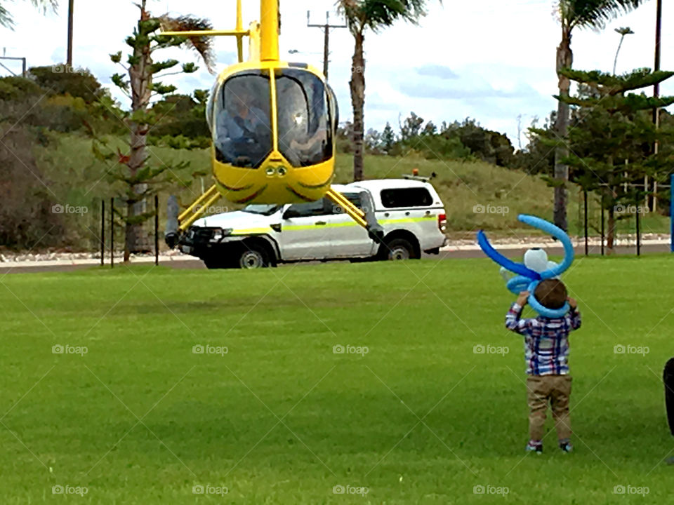Yellow Helicopter taking off in park, child foreground