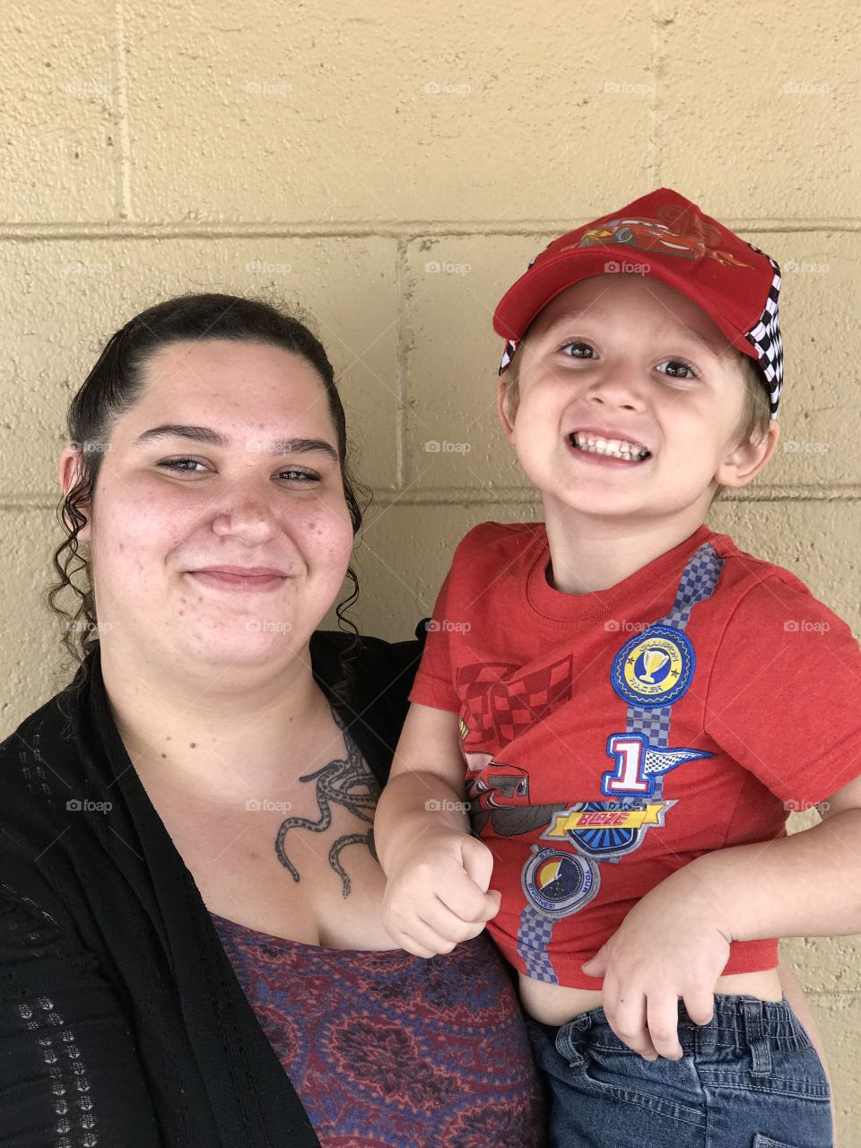 A adoring young mother holds her son who’s full of joy and happiness. 