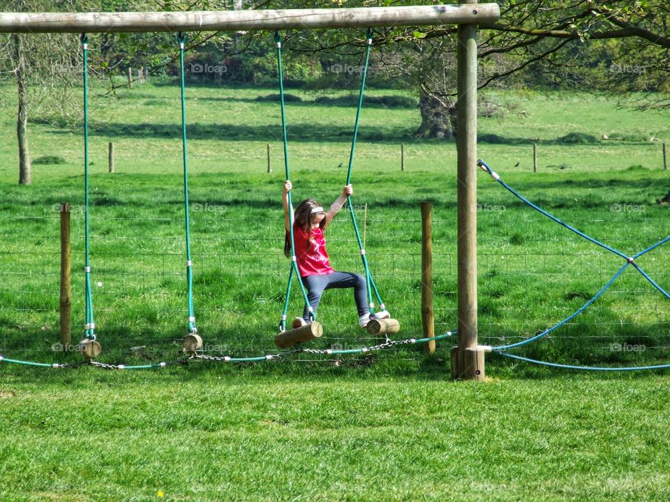 Girl walking across a rope bridge.