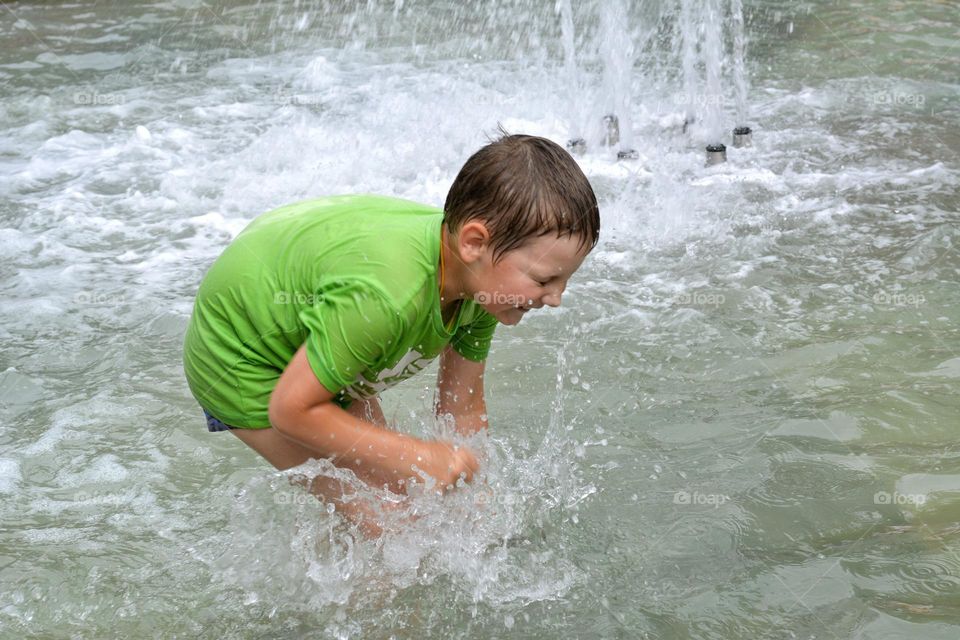 child in water fountain city summer time