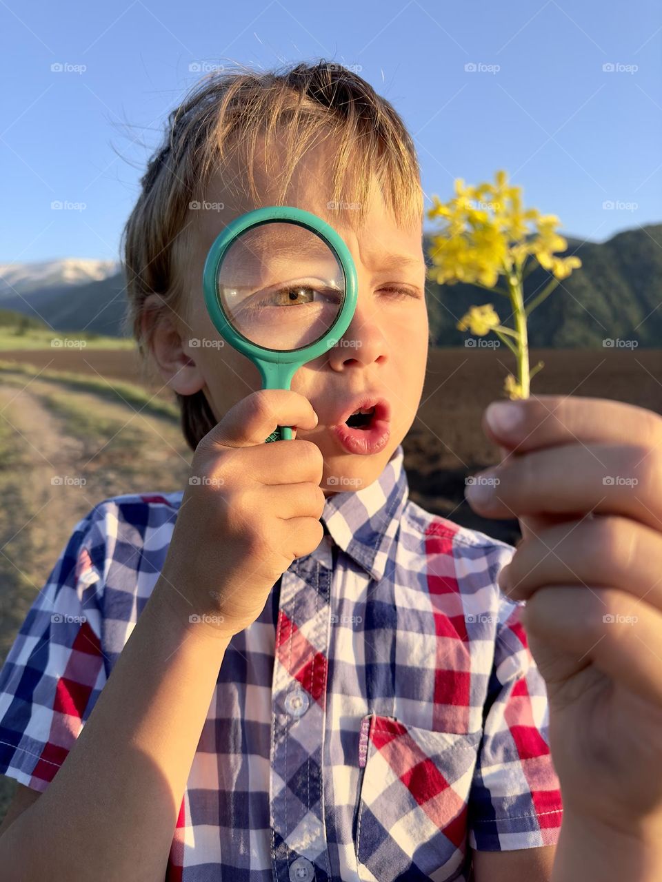 Boy looking at a flower through a magnifying glass