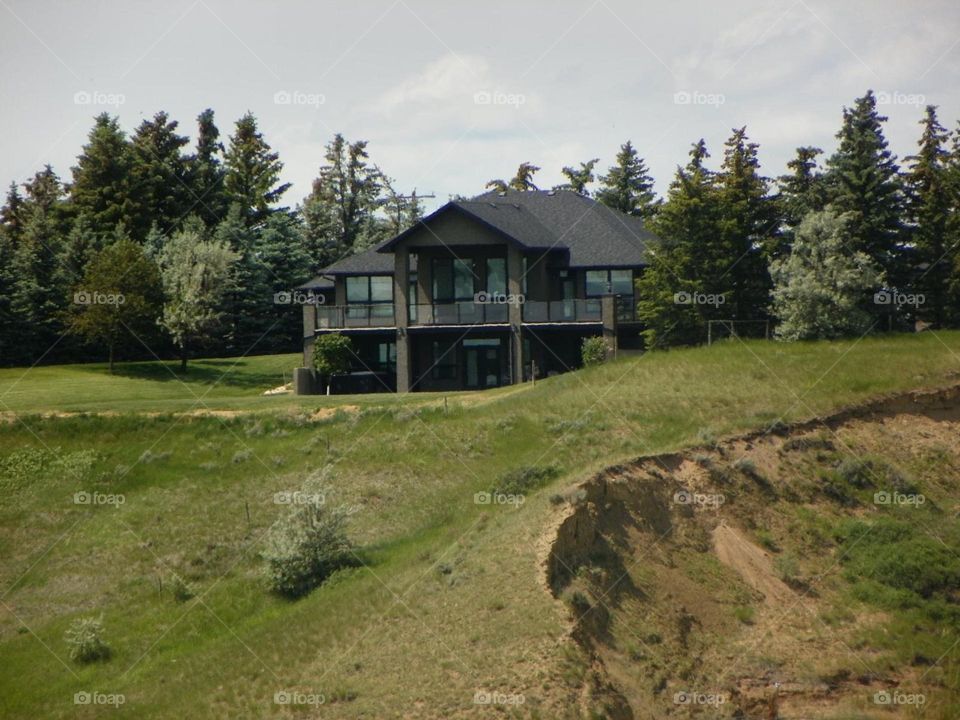 This landscape picture shows a Big house facing overlooking a golf course and coulees in Medicine Hat, Alberta, Canada 