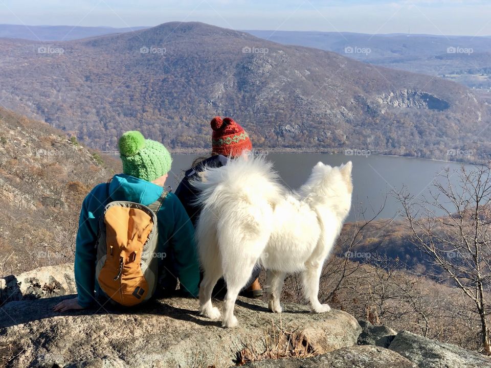 Two hiker women  sitting on a rock with a white dog