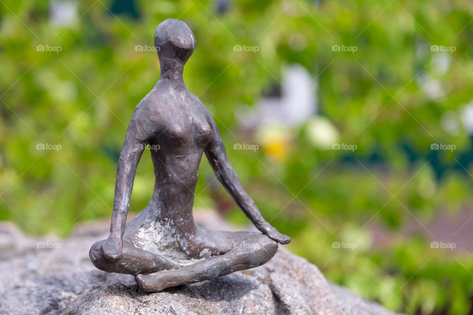 Metal yoga figurine on the rock, symbol of inner peace and balance