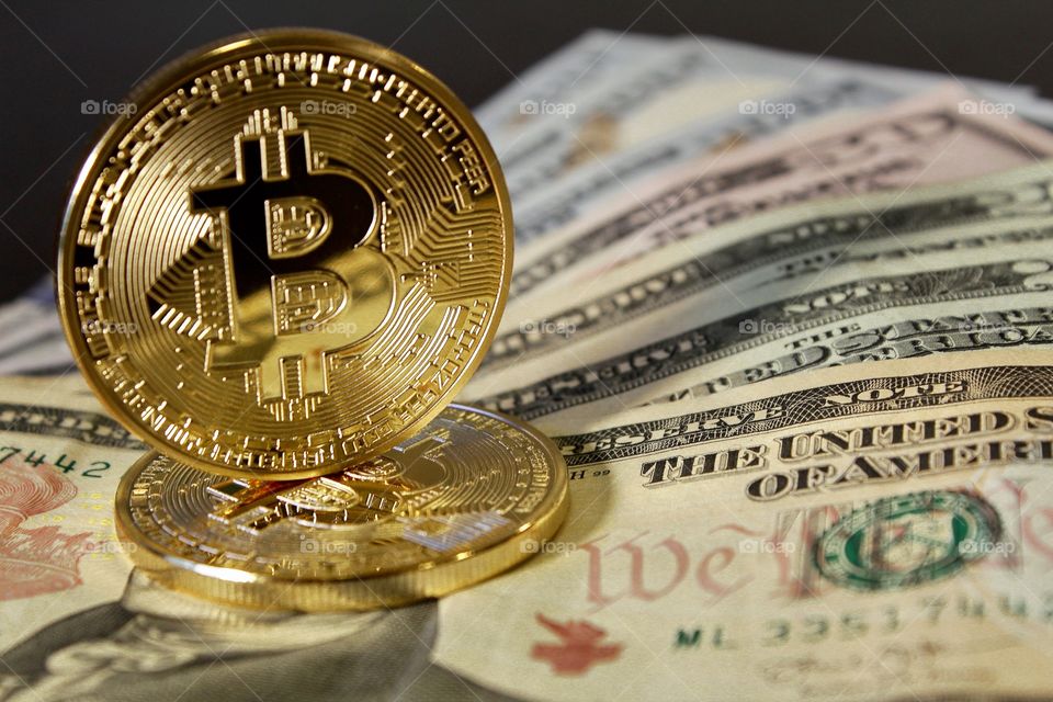 Bitcoins balanced over cash bills 