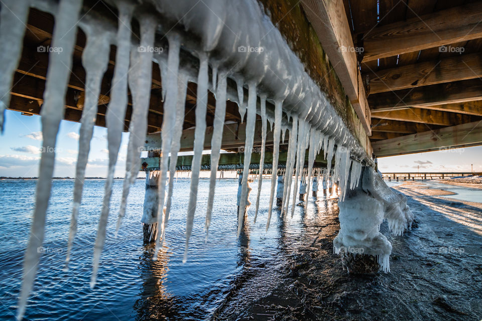 Icicles forming underneath a frozen pier.