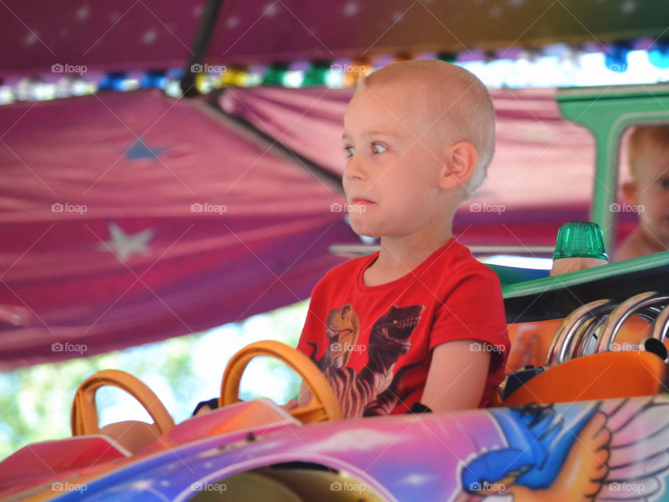 Boy driving a car on the amusement park
