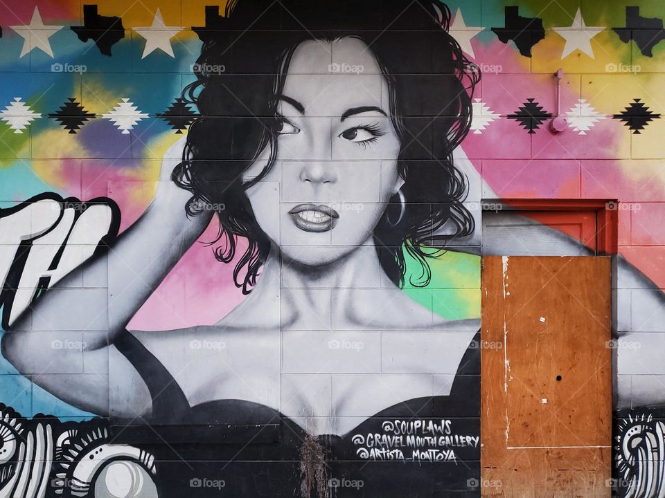 Visual urban street art closeup of a portrait of a women painted in black and white surrounded by a bright colorful background.