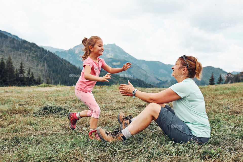 Little girl laying playing on grass enjoying summer day. Happy child playing in the field during vacation trip in mountains