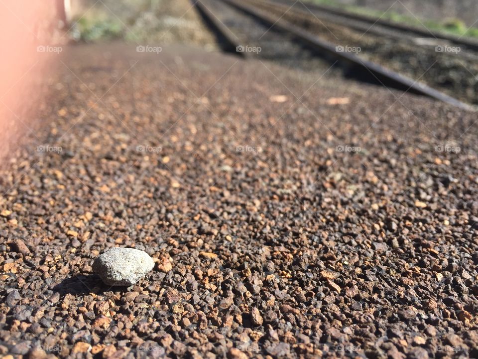 Train tracks with a singular rock on the platform