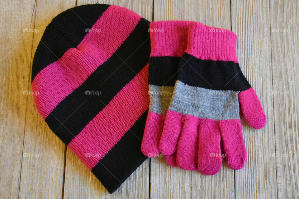 Colorful winter gloves and hat on wood background