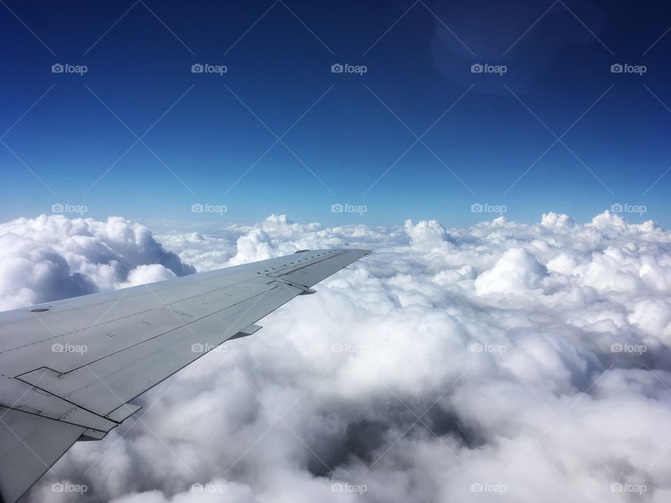 Airplane wing over cloudy Earth