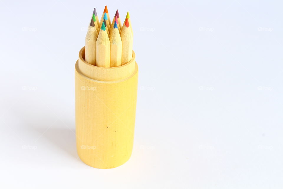 Group of color crayons in a wooden cylinder isolated macro