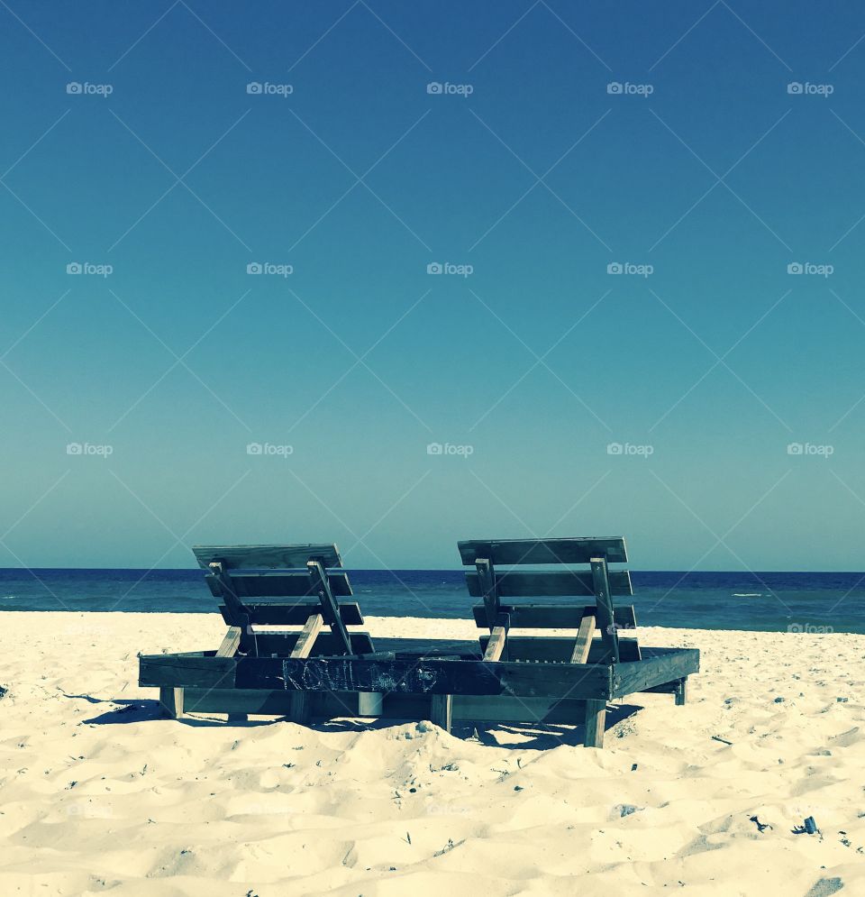 Wooden chairs for lounging on the sand on the beach. 