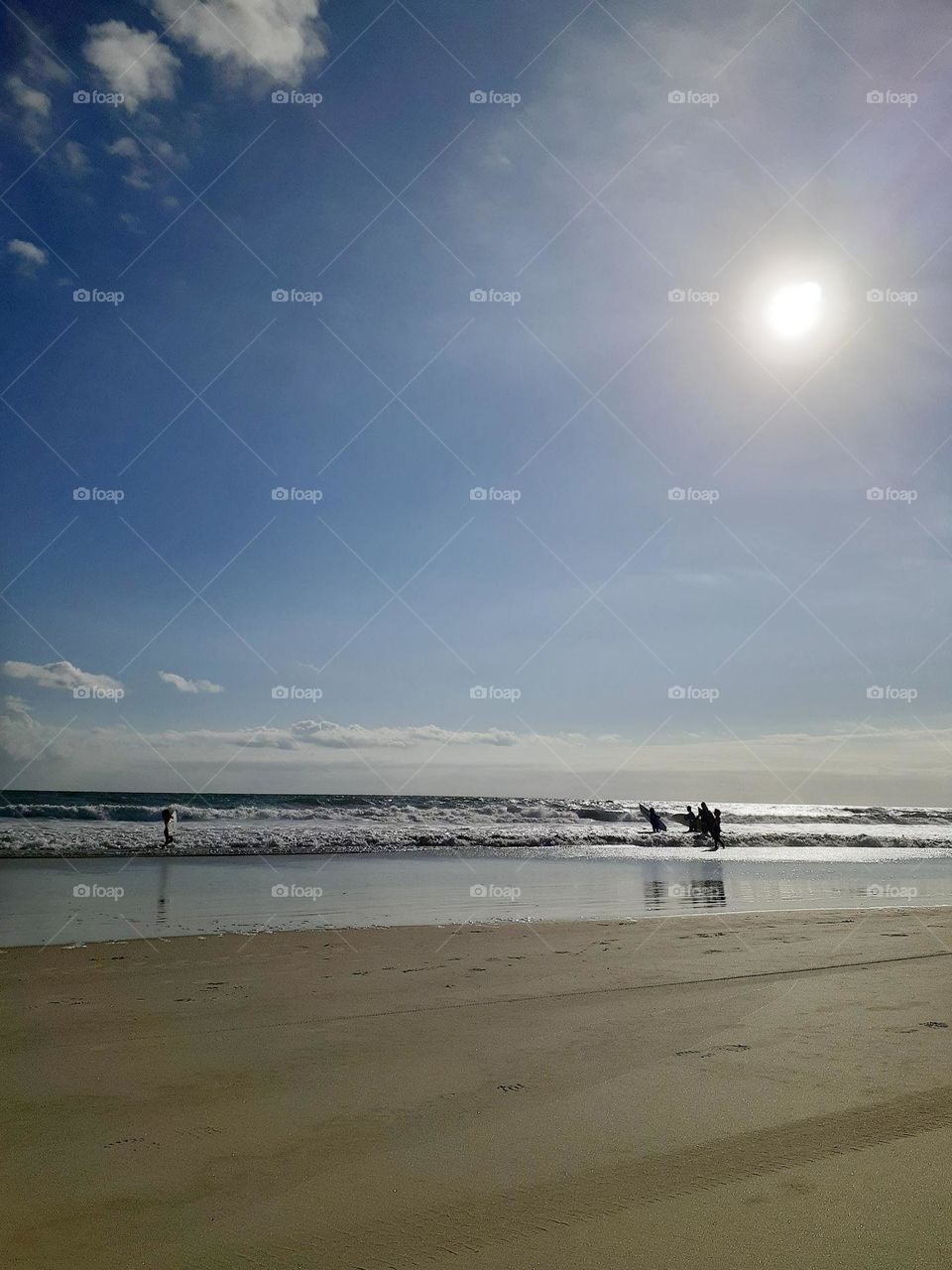 A group of surfers carries their surfboards into the Ocean to surf at Indian Rocks Beach in Tampa, Florida.