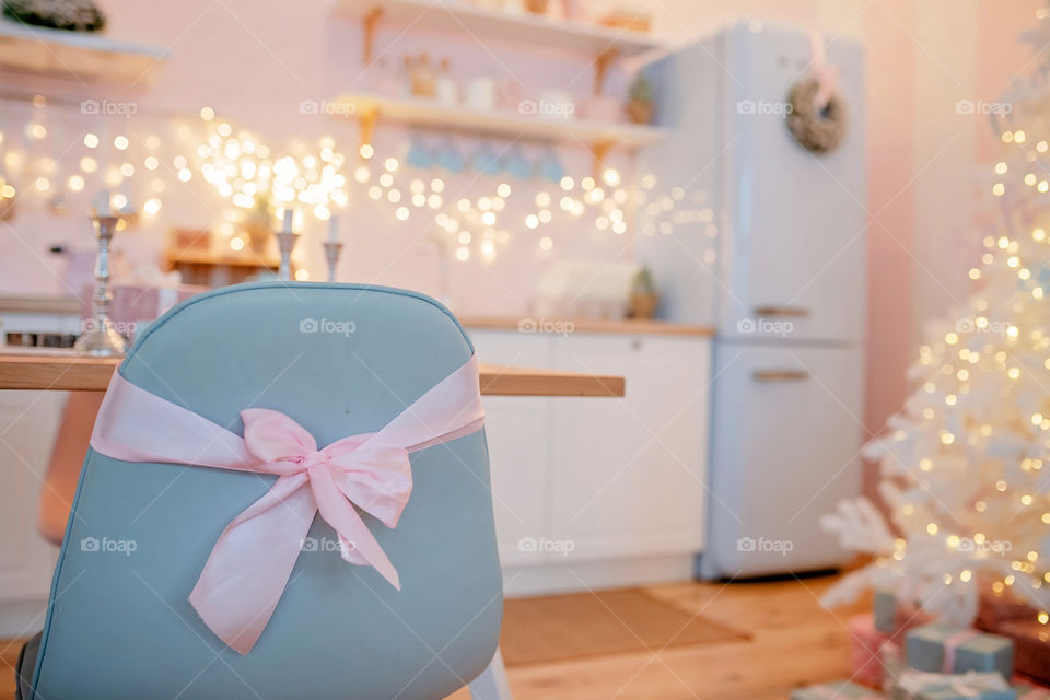 Festive winter cozy kitchen interior with garlands, decorations and gifts.  Christmas dinner at the decorated table.