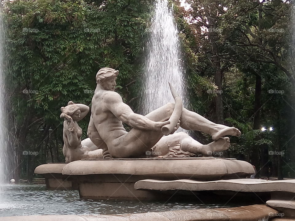 Sculpture of a man over a water fountain. It's located in Caracas, Venezuela in a Park called "Los Caobos".
