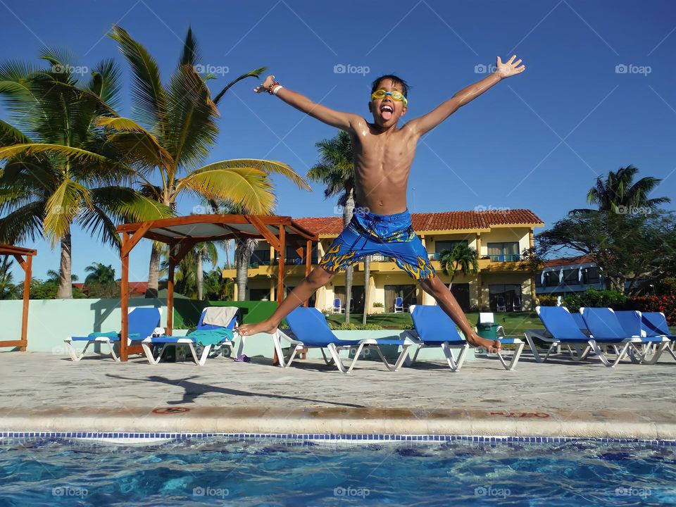 Happy cute little boy jumping into the pool