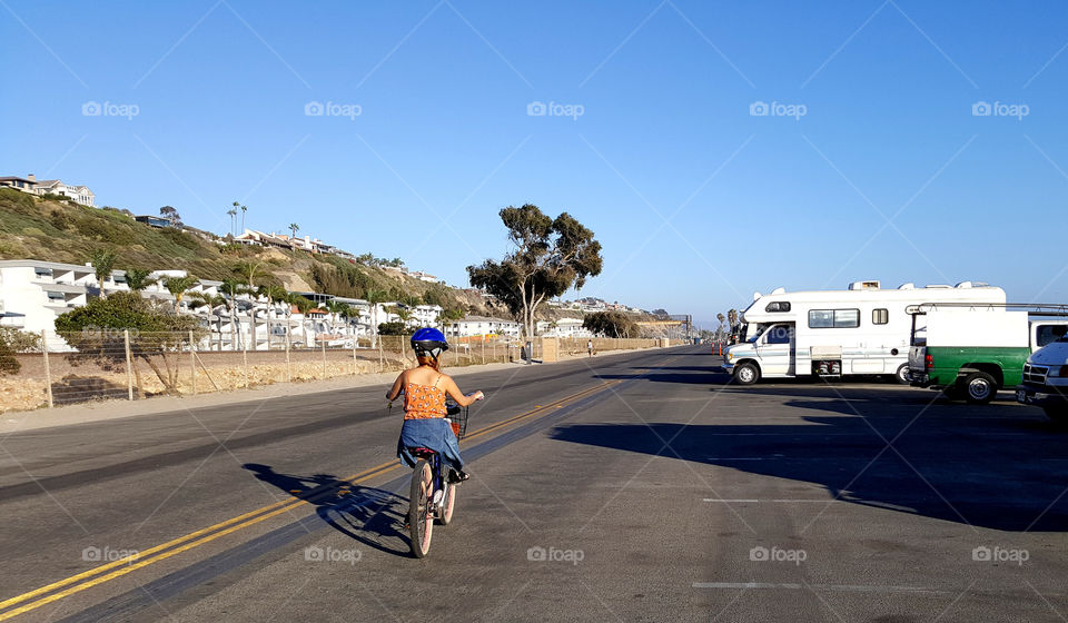 photo story, girl biking in the city, at the street where RVs are parked