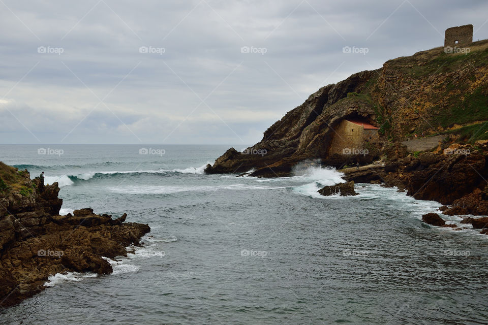 View of Santa Justa beach and chapel excavated in the cliffs, Cantabria, Spain.