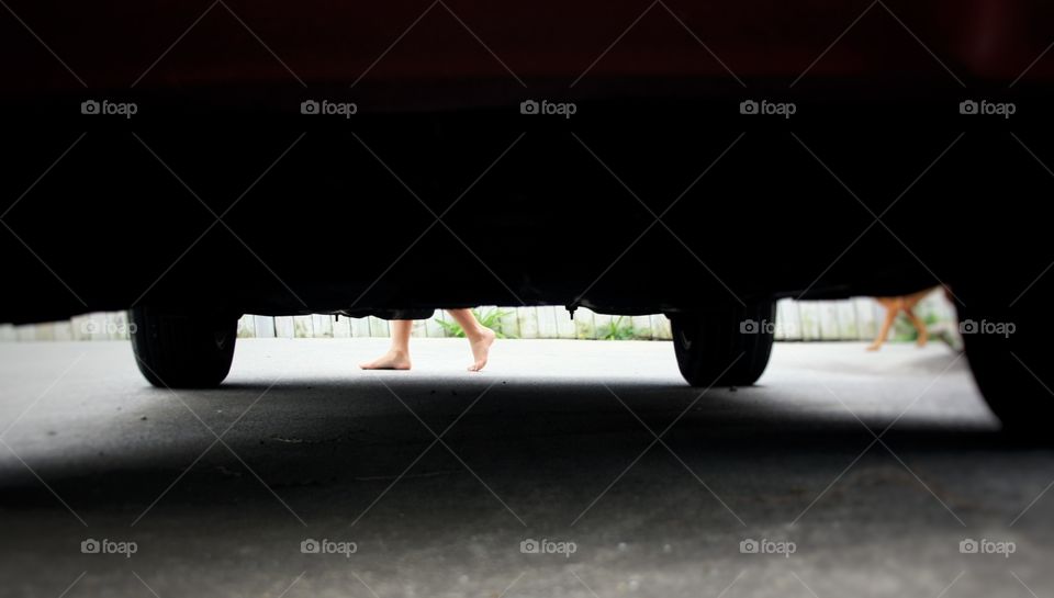 Kids legs passing by at the rear end of a parking car