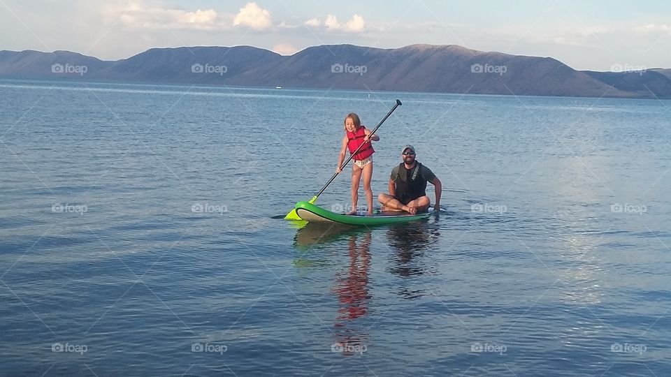 Father and daughter stand up paddle boarding in lake