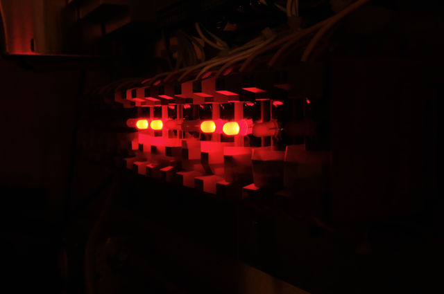 View in the dark of a row of solid state relays with red LED lights used for data acquisition and control systems. 