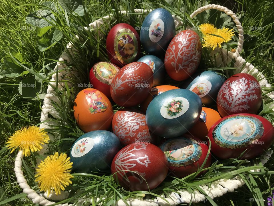 Easter eggs in a basket in the grass on Easter day, there are different colors of them.